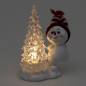 Preview: leuchtender-LED-Tannenbaum-daneben-Schneekind-mit-roter-Strickmütze